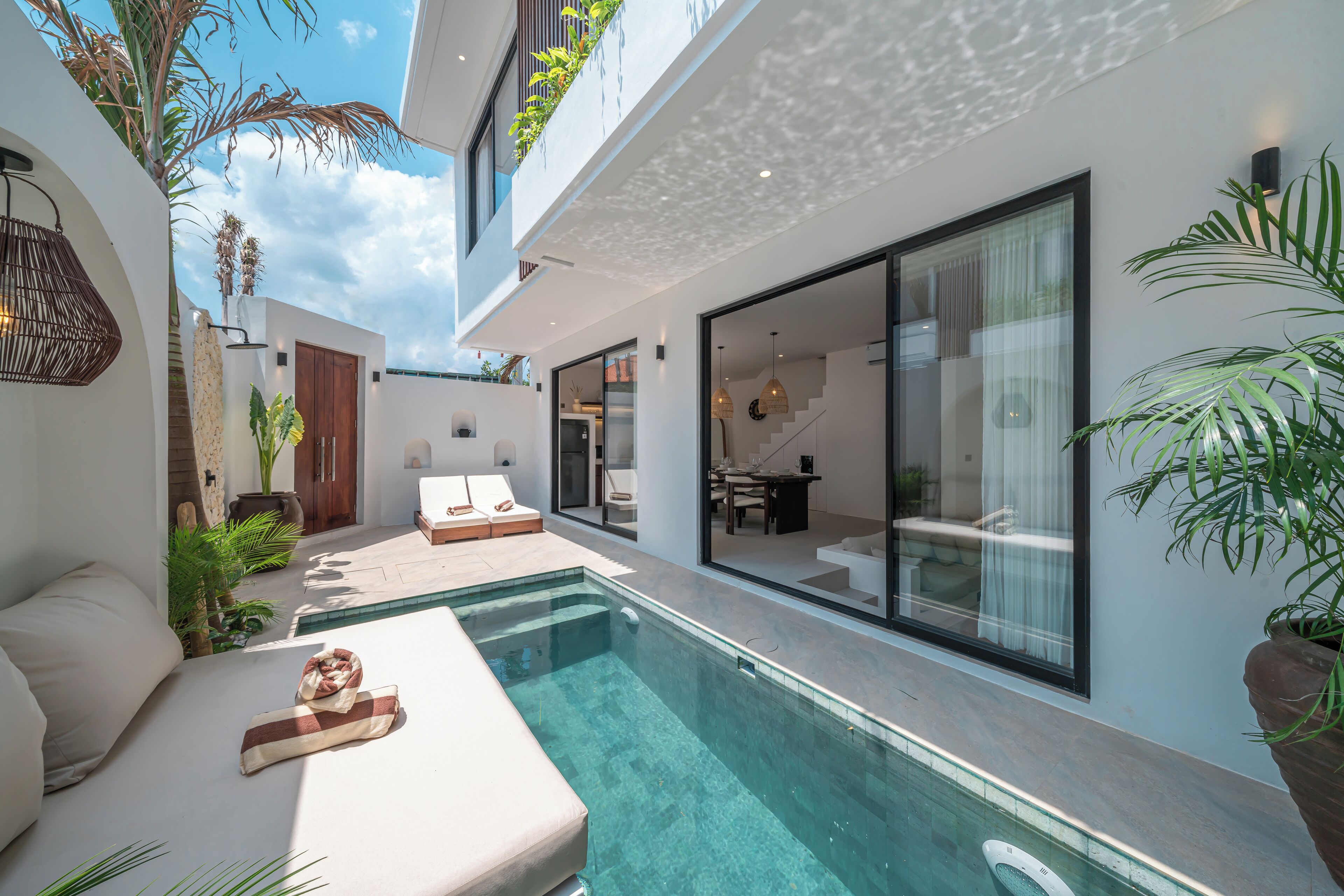 A modern house with a swimming pool, a dining area, and a living room with a sofa and a table.