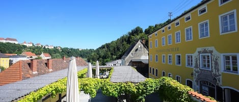 A yellow building with the name "Weinhaus Pachler" and a view of a town with red-roofed buildings and a hill in the background.