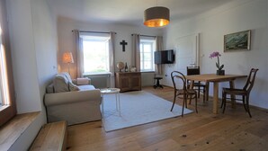 A living room with a sofa, a dining table with chairs, a TV, a globe, and a cross on the wall. - Vacation apartment with an excellent view (Ach)