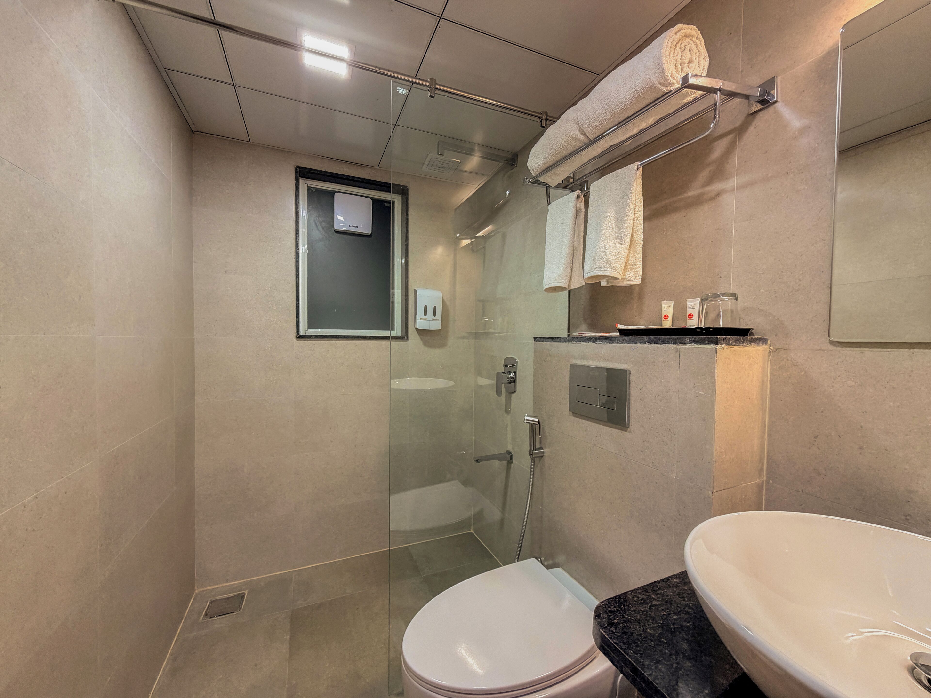 Et moderne badeværelse med en glasvæg omkring bruseren, et hvidt toilet og en vaskemøbel med vask.