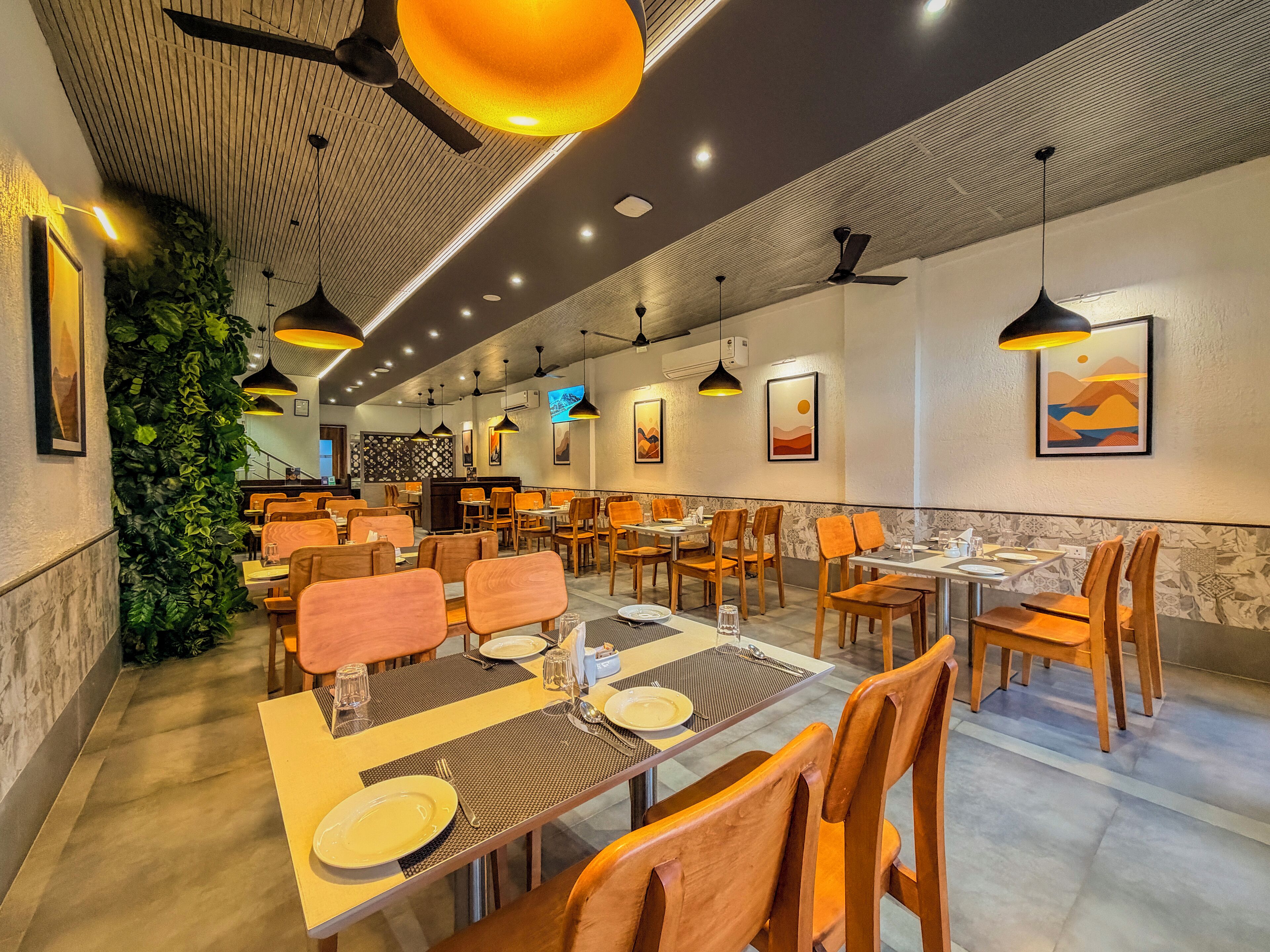 A restaurant with multiple dining tables and chairs, ceiling fans, and wall-mounted artwork.
