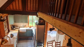 Interior acogedor de una cabaña con cocina, comedor y una cama.