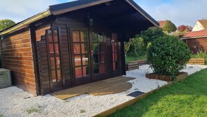 Una cabaña de madera con un porche cubierto, un camino de grava y un pequeño jardín.