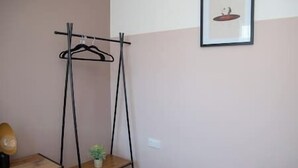 Une pièce avec une commode en bois, un portant à vêtements et une petite plante en pot.