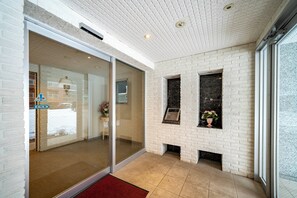 A modern lobby with a glass door entrance, a fireplace, and a tiled floor. - COURT VILLA SAPPORO 102 (Sapporo)