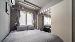 A modern bedroom with a large bed, a desk, and a chair. - COURT VILLA SAPPORO 102 (Sapporo)