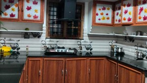A kitchen with wooden cabinets, a stove, and a window. - A one Cottage Munnar (Anachal)