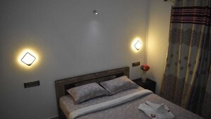 A neatly made bed with a wooden headboard, two bedside lamps, and a decorative vase with flowers on a nightstand. - A one Cottage Munnar (Anachal)