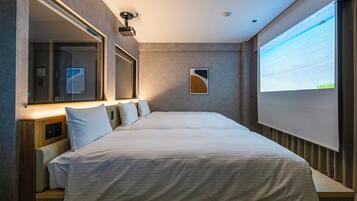 A modern hotel room with a large bed, a wall-mounted projector, and a large window with a view.