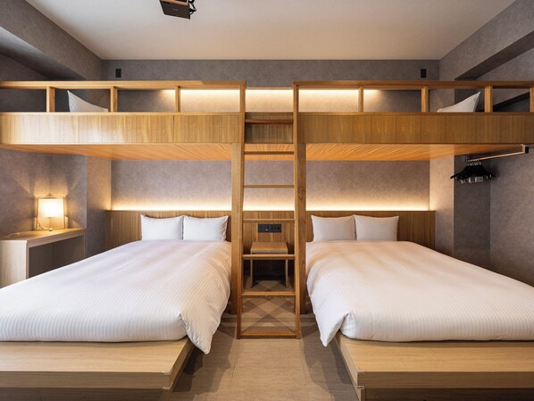 Una camera con un letto a castello, due letti, un comodino, una lampada e una scala in legno.