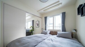 A bedroom with a large bed, a bedside table, a lamp, a window with curtains, and a mirror. - COURT VILLA SAPPORO 403 (Sapporo)