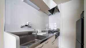 A modern kitchen with a stainless steel sink, white cabinets, a black refrigerator, and a built-in oven. - COURT VILLA SAPPORO 403 (Sapporo)