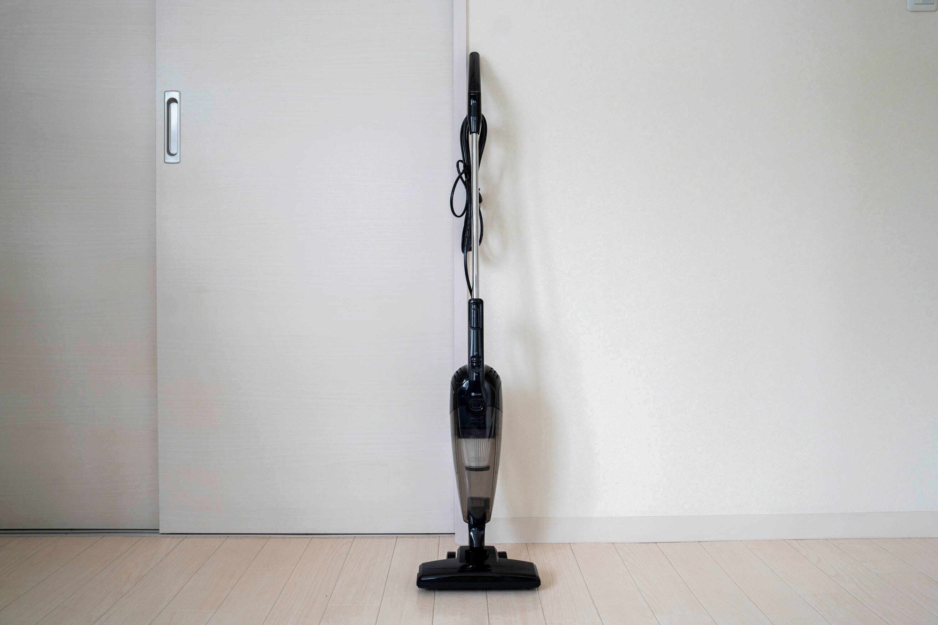 A vacuum cleaner in a room with a wooden floor and a white door.