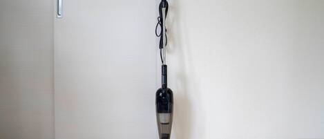 A vacuum cleaner in a room with a wooden floor and a white door.
