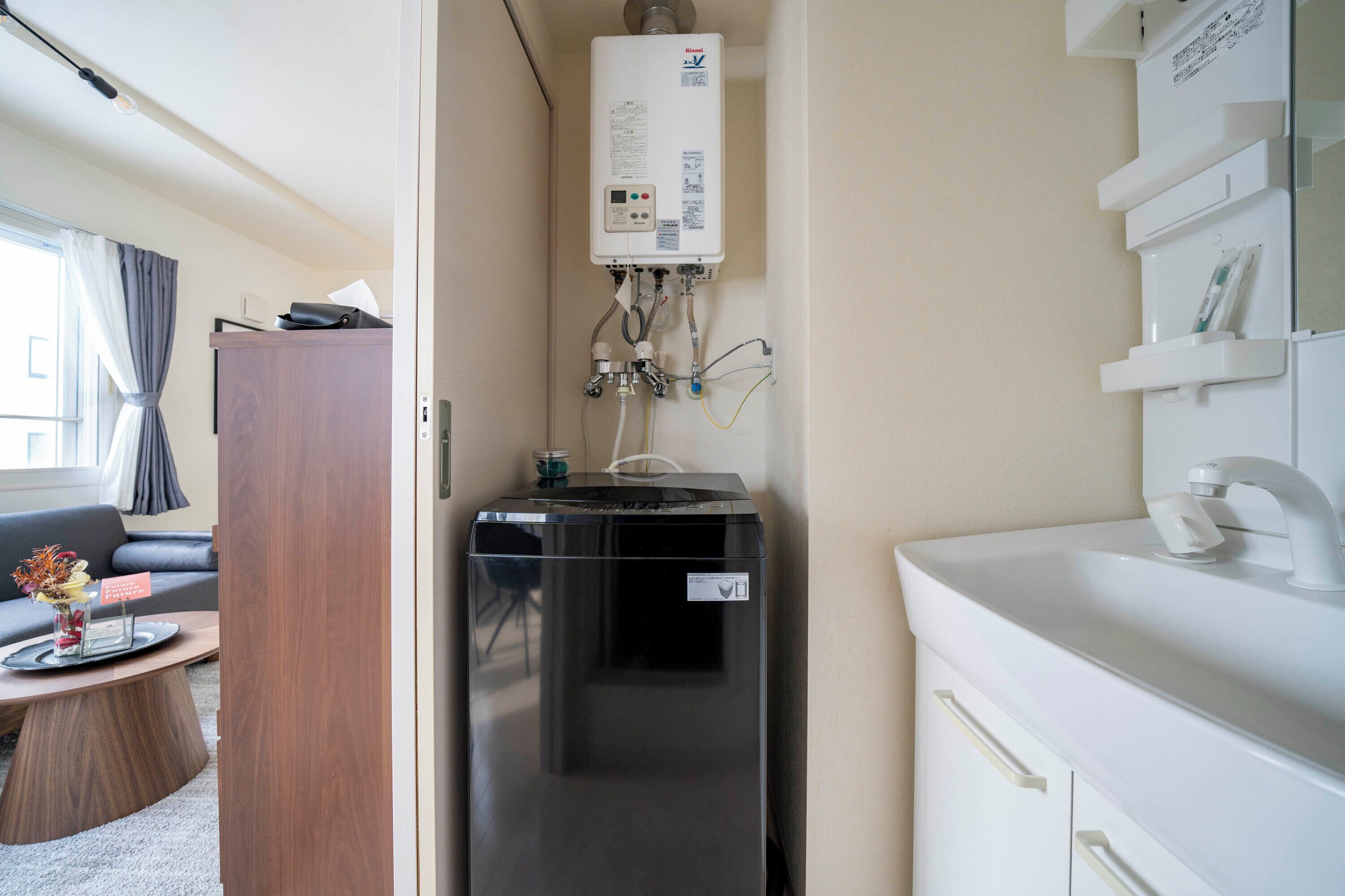 Ett kompakt kök med en inbyggd diskmaskin, en vit bänkskiva och en väggmonterad varmvattenberedare.