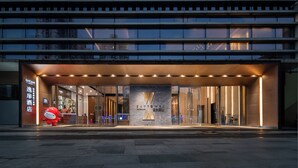 A modern hotel entrance with a prominent 'X' logo, glass doors, and a red mascot outside. - UrCove by Hyatt Shenzhen Bay Nanyou (Shenzhen)