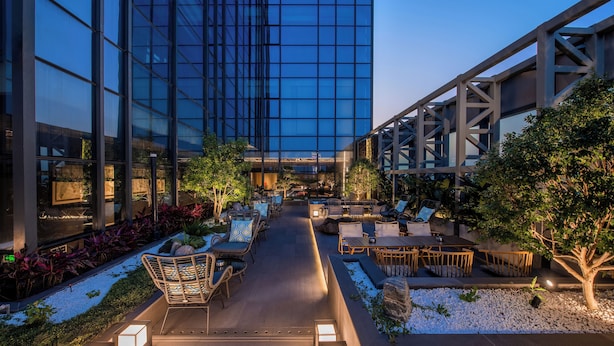 An outdoor lounge area with seating and a pathway leading to a building entrance. - UrCove by Hyatt Shenzhen Bay Nanyou (Shenzhen)