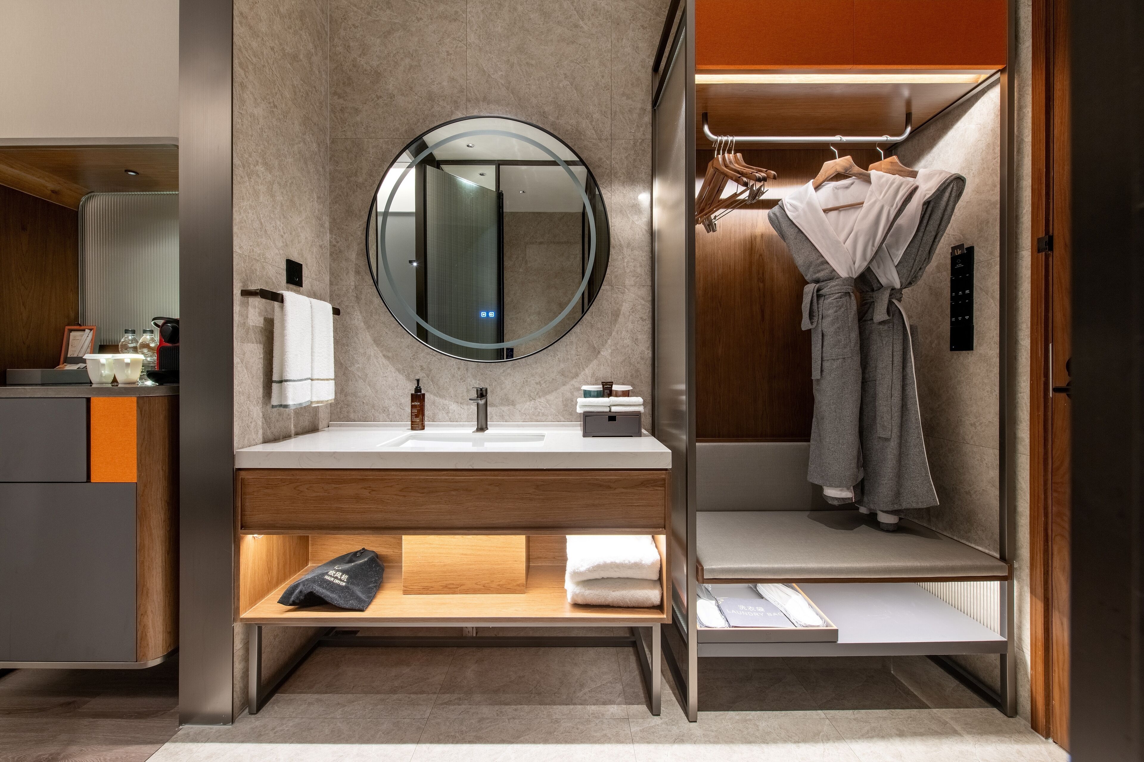 A modern bathroom with a double sink vanity, a large mirror, and a robe drying rack.