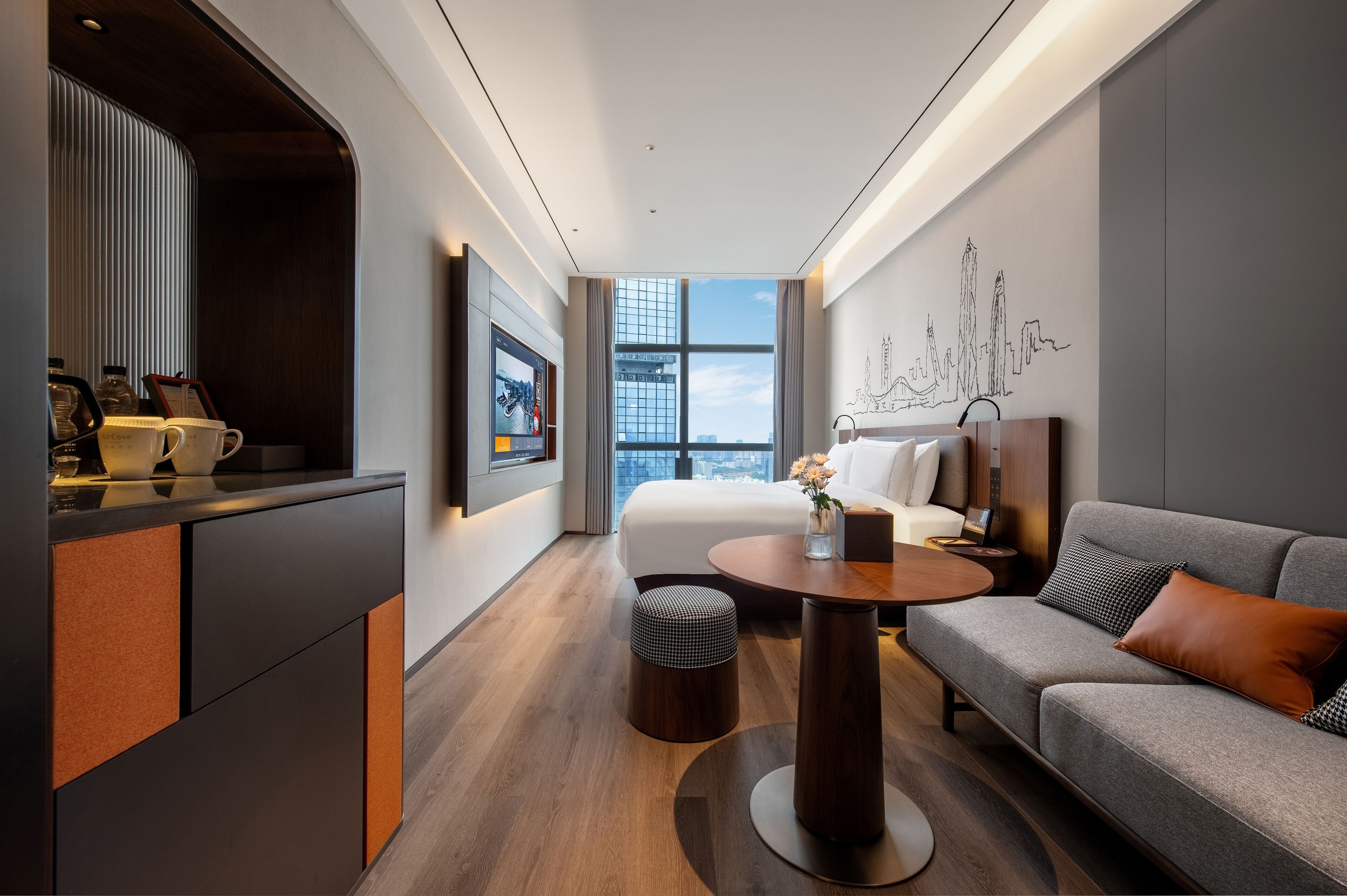 A modern hotel room with a bed, sofa, and a small dining area.