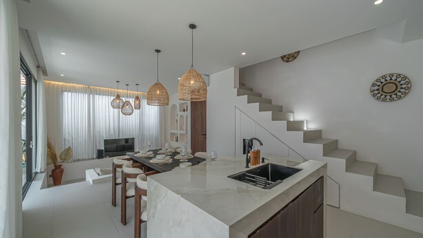 Een moderne keuken met een marmeren eiland, hangende lampen en een inbouwoven.