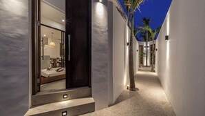 A modern hotel corridor with a staircase leading to a room, palm trees, and a well-lit interior. - Nova Oasis 3 (Canggu)