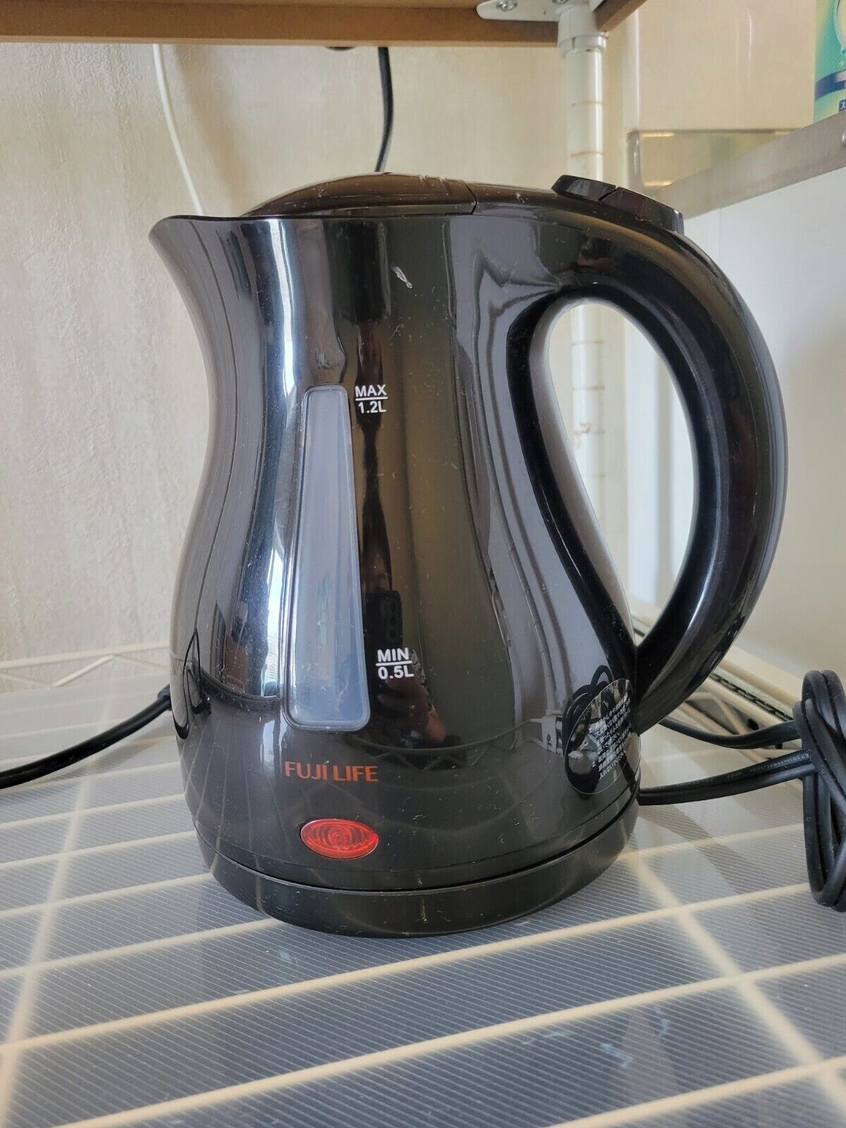A black electric kettle with a handle, labeled 'FUJIFILM' and 'MAX 1.2L'.