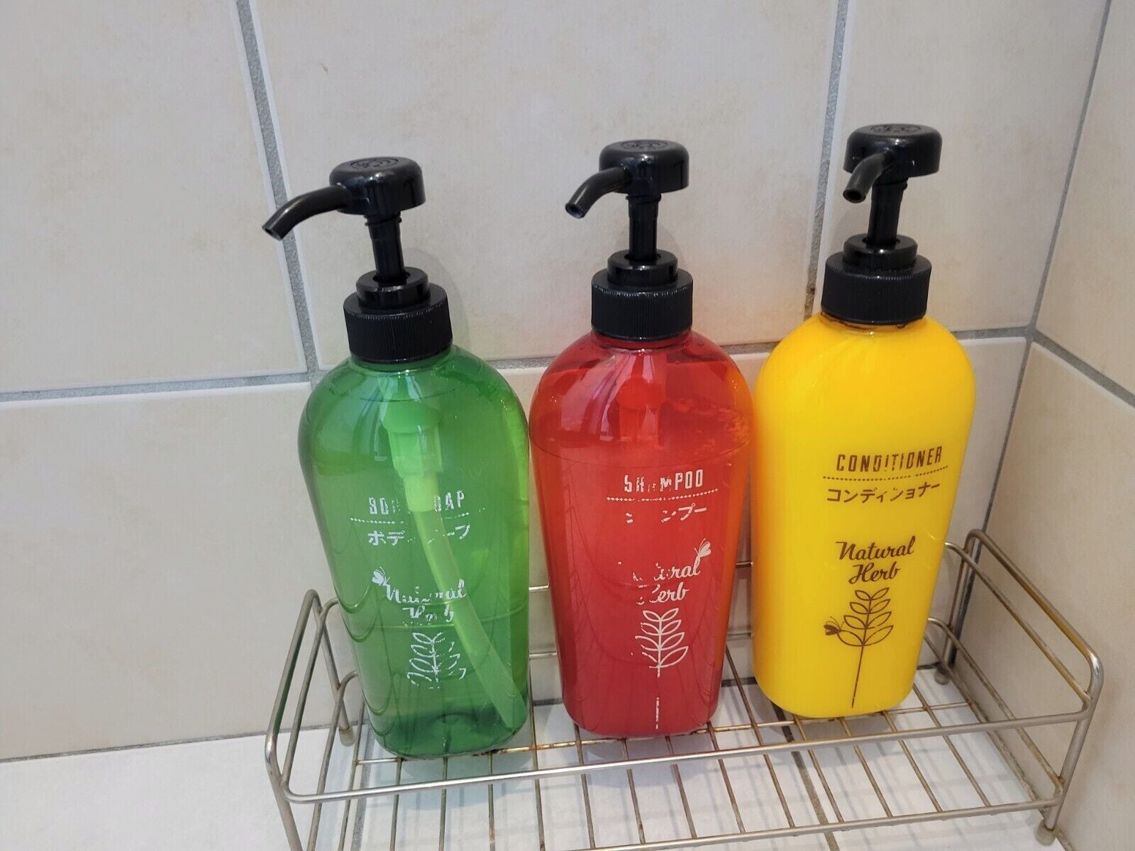 Three bottles of liquid soap on a metal shelf.