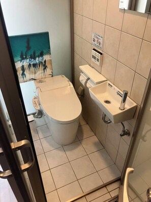 A small bathroom with a toilet, sink, and a wall-mounted control panel. - New Normal Condo in KENCHOMINAMIGUCHI (Naha)
