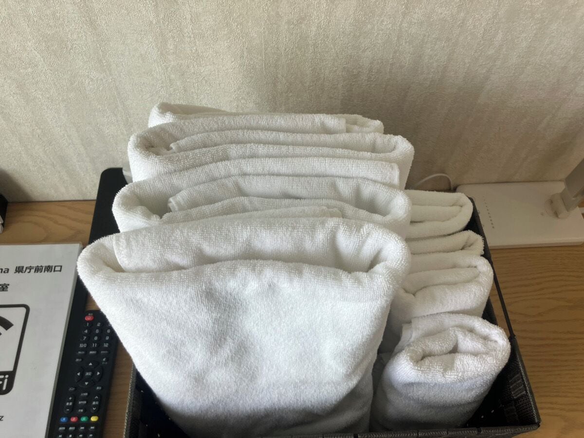 A stack of white towels in a black tray on a wooden table.