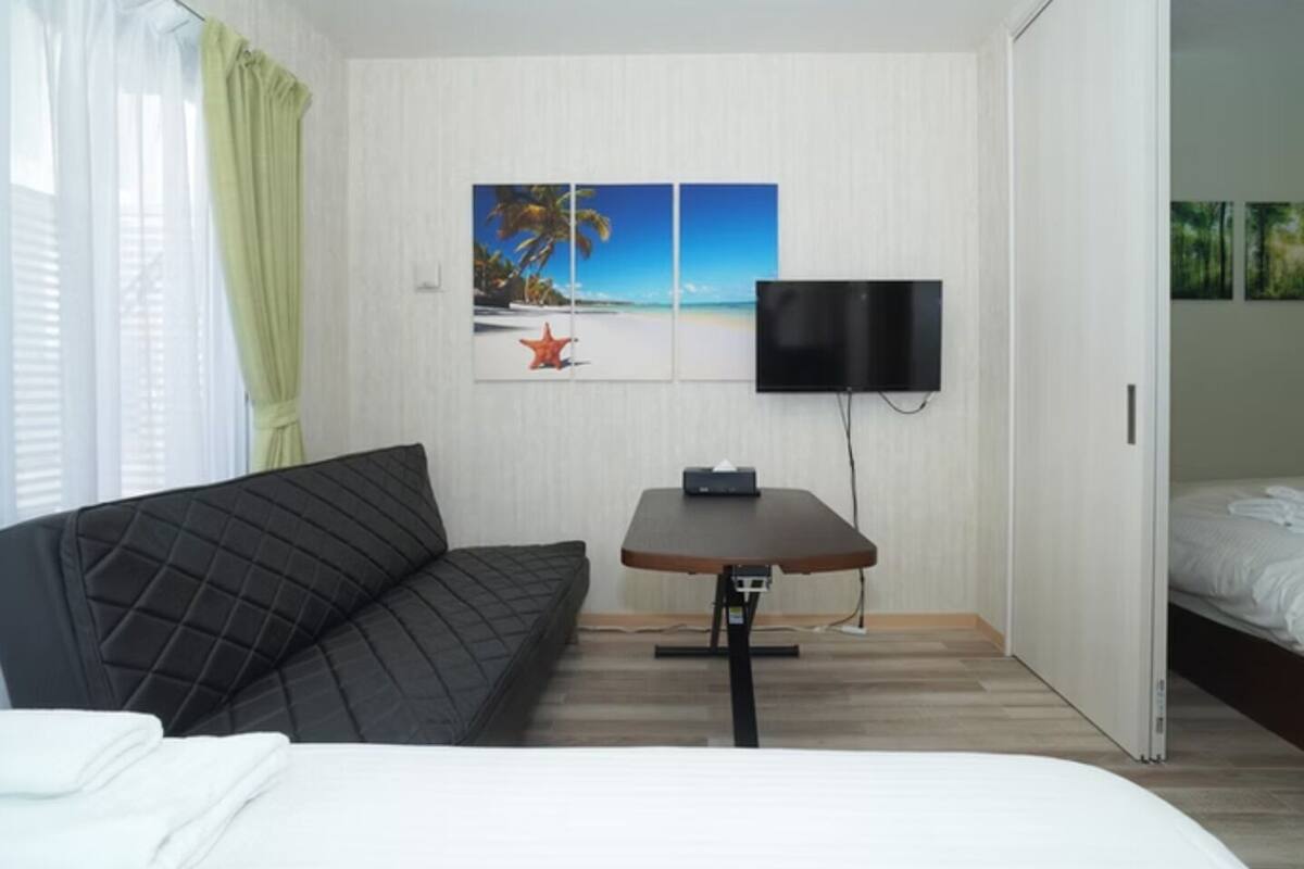A hotel room with a bed, a sofa, a table, and a TV.