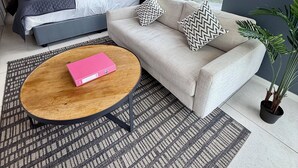 A modern hotel room with a bed, a sofa, a coffee table, and a large window offering a city view. - Urban Elephant The Rose (Cape Town)