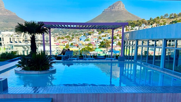 A rooftop pool with a view of a colorful town and mountains. - Urban Elephant The Rose (Cape Town)