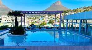 Una piscina en la azotea con vistas a un pueblo colorido y montañas.