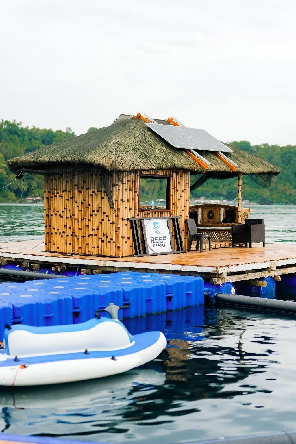 A floating structure with a thatched roof, a sign reading 'REEF RESORT,' and a small bar area.