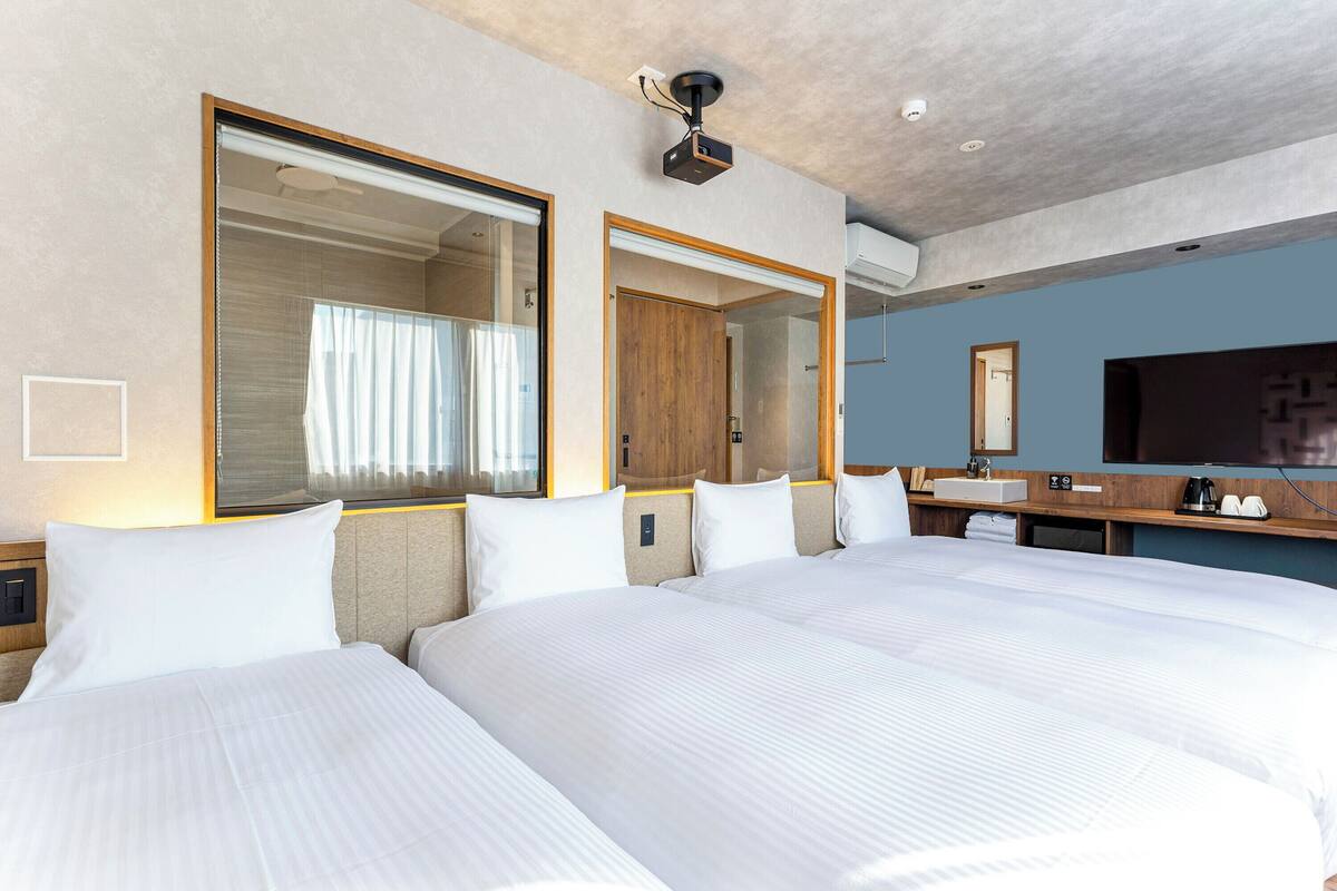 Ein Hotelzimmer mit zwei Betten, einem großen Spiegel, einem Fernseher und einer Minibar.