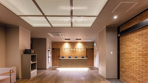 Un'area reception con pavimento in legno, una scrivania della reception, una parete con motivo a mattoni e un soffitto con design a griglia.