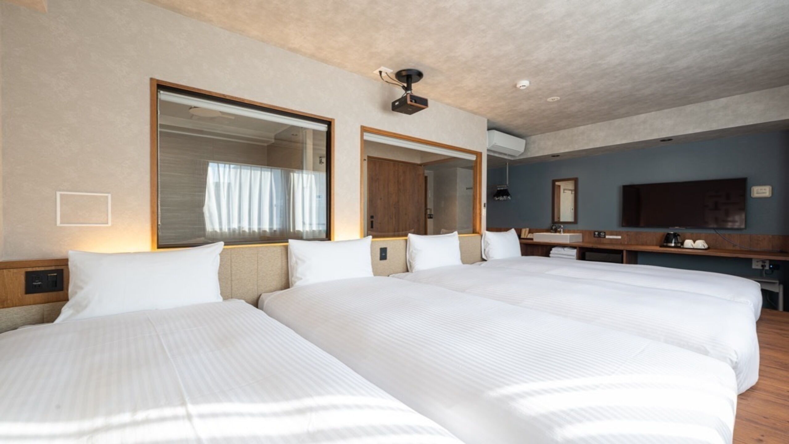 Una habitación de hotel con dos camas grandes, televisión, baño y ventilador de techo.