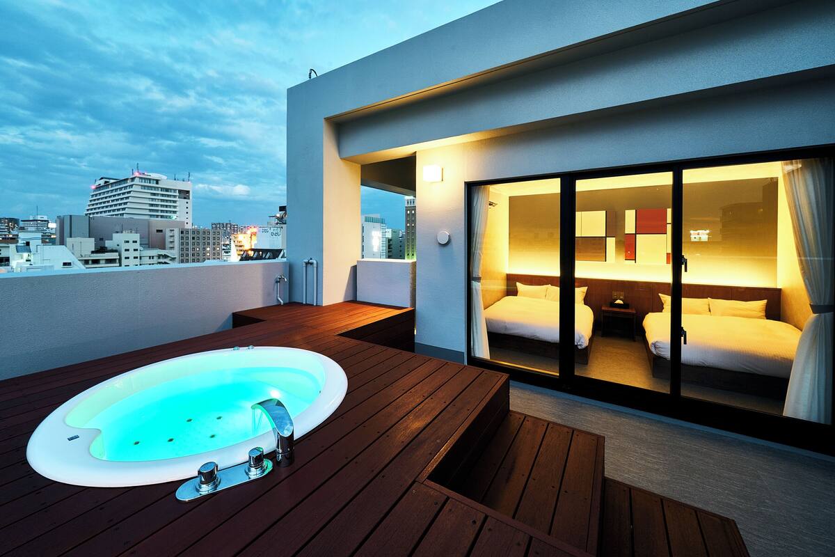 Ein modernes Hotelzimmer mit einer großen Schiebeglasdoor, einer Holzterrasse und einem Whirlpool.