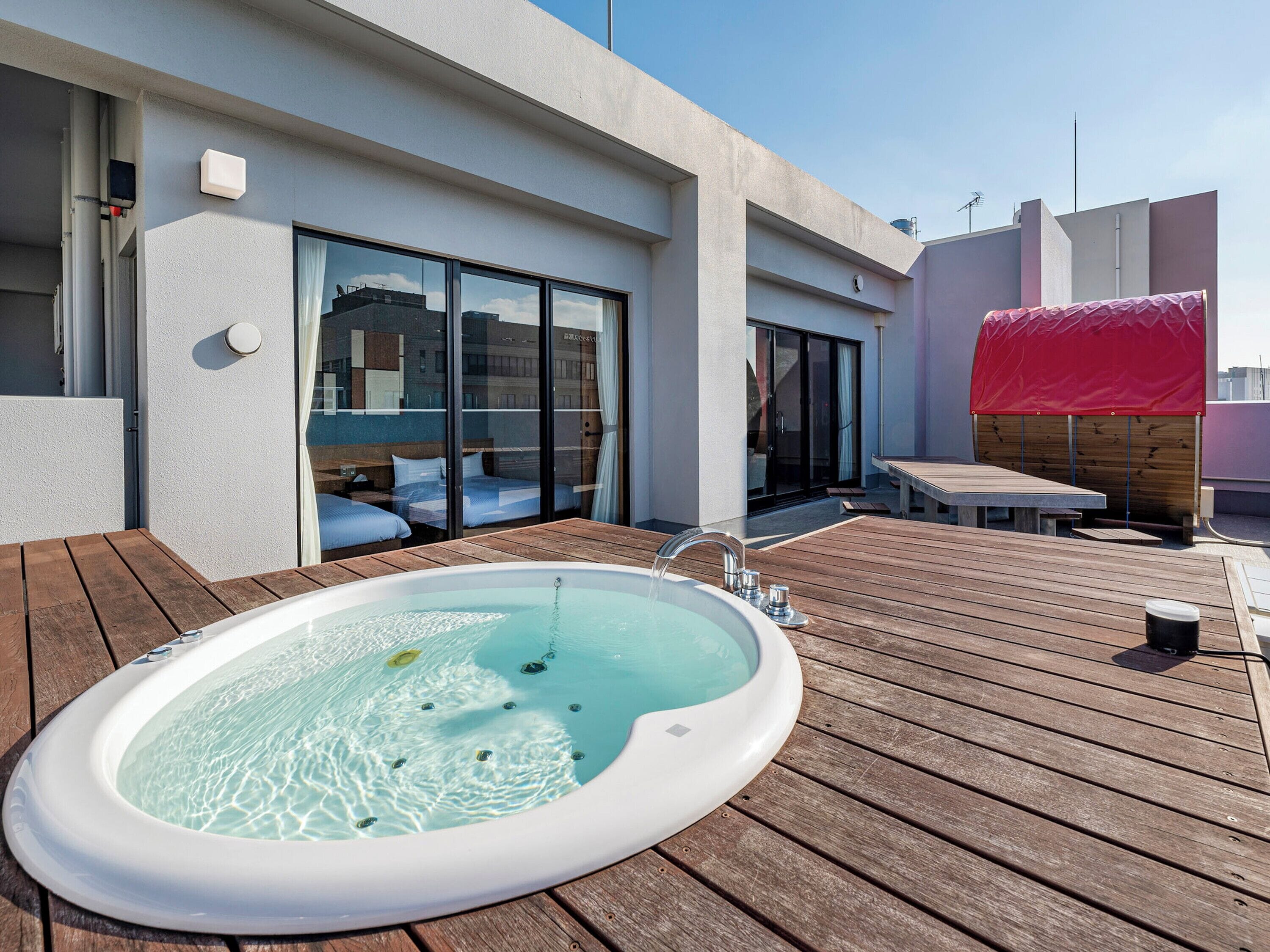 Una terraza en la azotea con jacuzzi, cubierta de madera, puertas correderas de cristal y un área de estar techada.