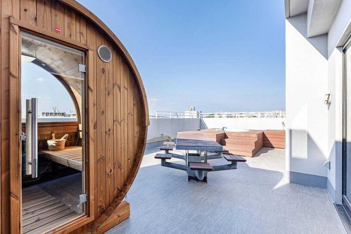 Eine Holzhütte mit Glastür, einem runden Tisch und Blick auf die Stadtlandschaft.