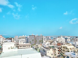 A cityscape with a variety of buildings, including residential and commercial structures, under a clear blue sky. - LACER OKINAWA NAHA MIEBASHI (Naha)