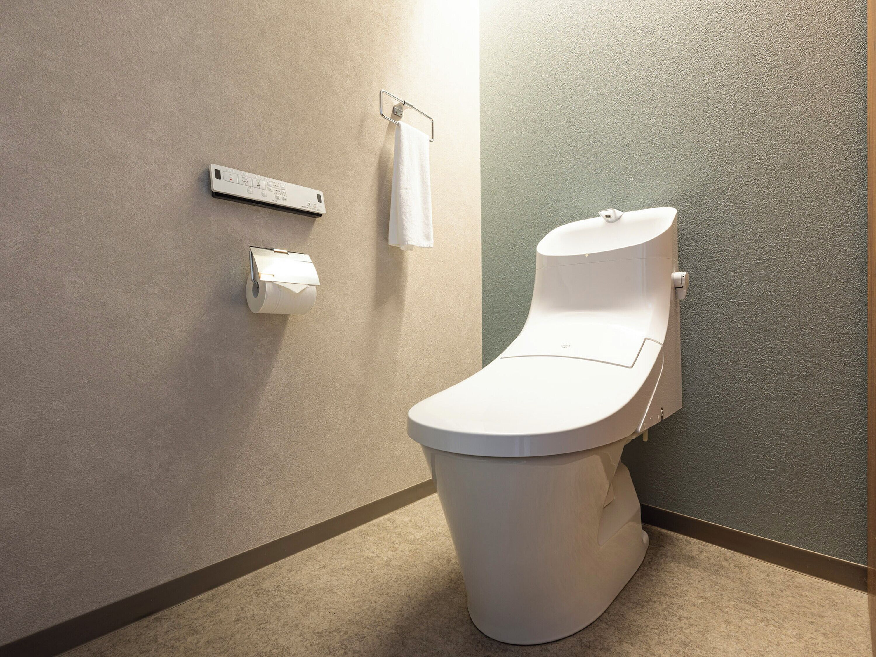 Un bagno moderno con il water bianco, un distributore di carta assorbente e un porta asciugamani.