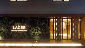 L'ingresso di un hotel con un cartello che riporta la scritta "Lacer Okinawa Naha Mie Bashi" e una fontana antistante.