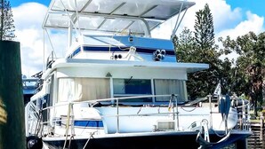 A white yacht docked at a marina with a covered deck and multiple levels. - 62' Yacht M/v Possibilities On Wide Private Canal 3 Bedroom Houseboat (North Fort Myers)