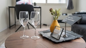 Ett rum med två tomma vinglas på ett runt träbord, en liten gul vas med blommor och en skylt med texten: ”Du är så vacker.”