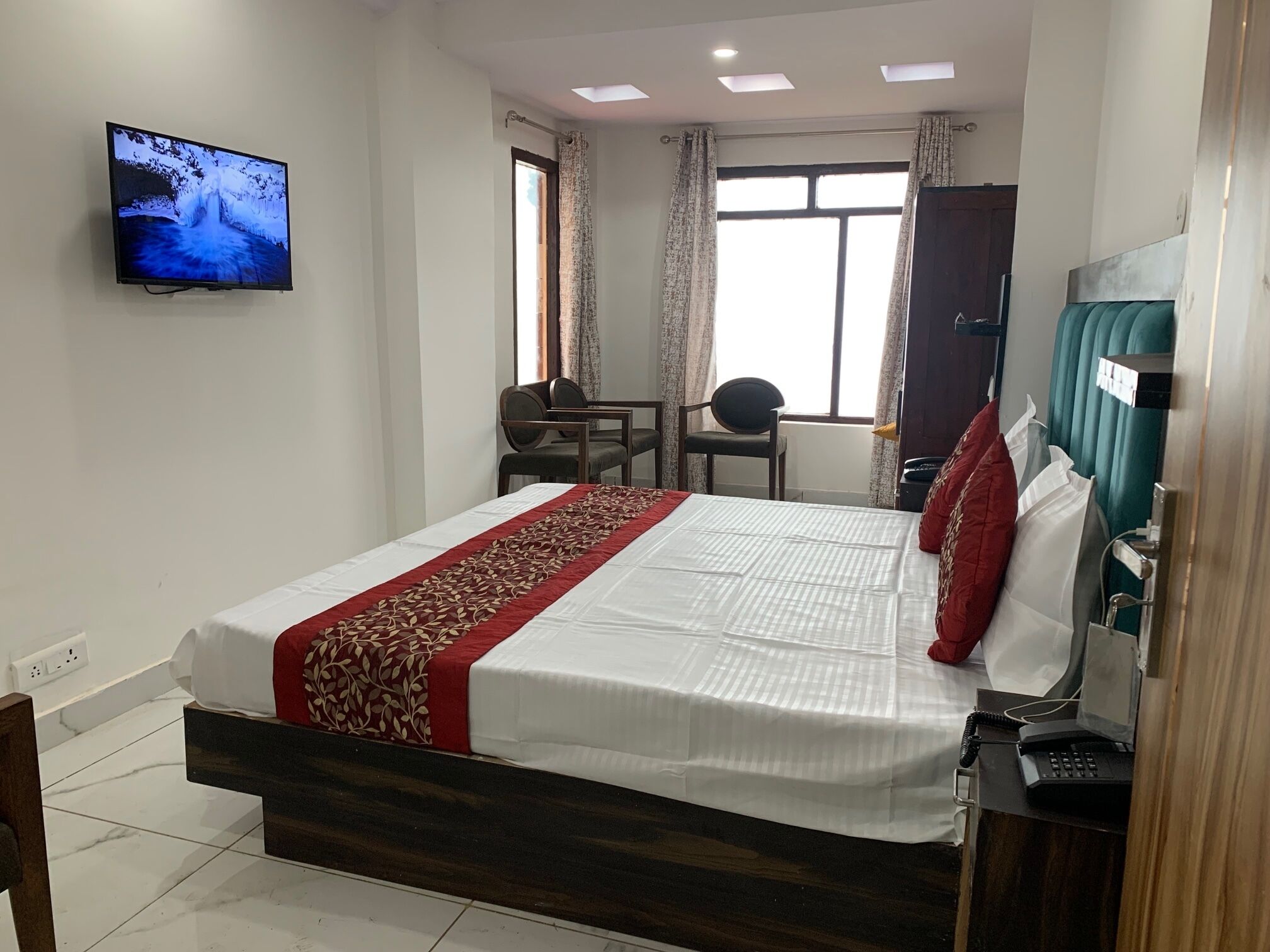 A hotel room with a bed, a desk, a chair, a television, and a window with curtains.
