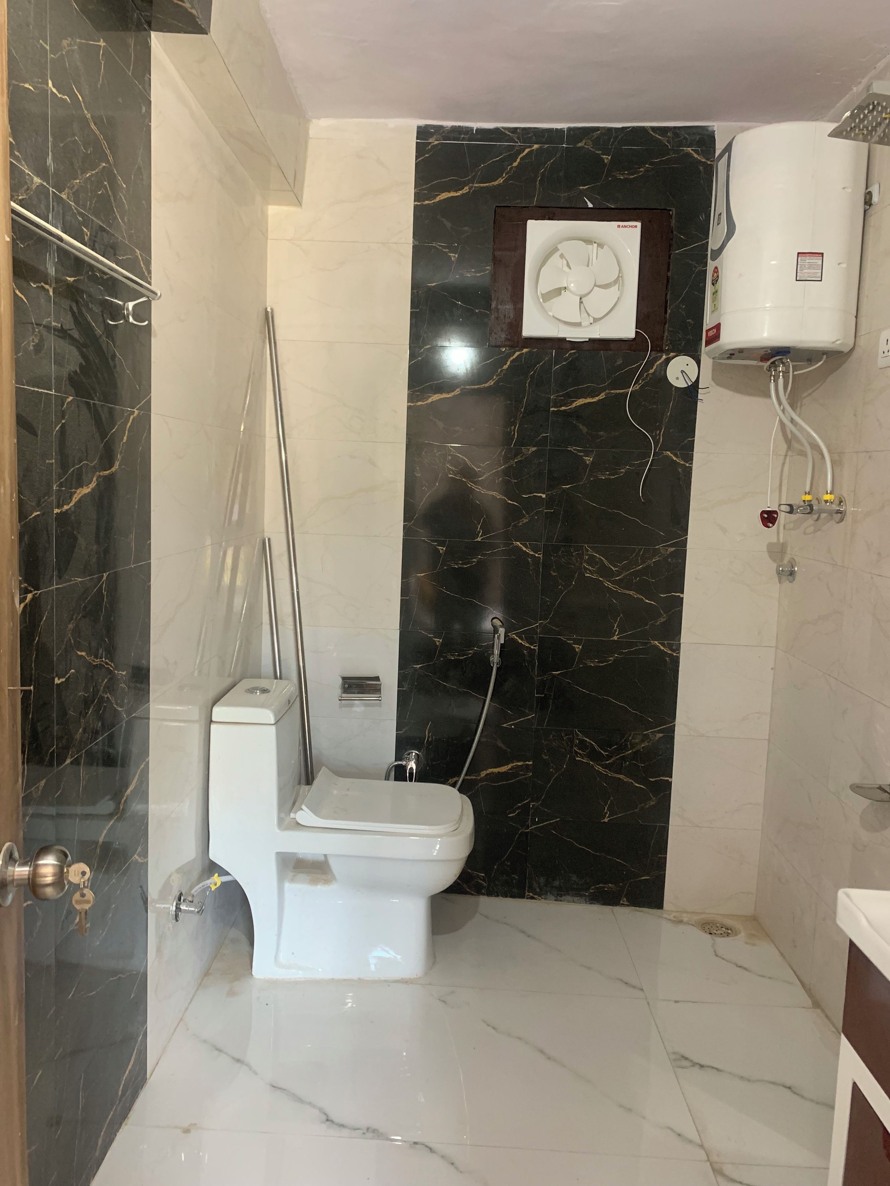 Een badkamer met toilet, douche en boiler.