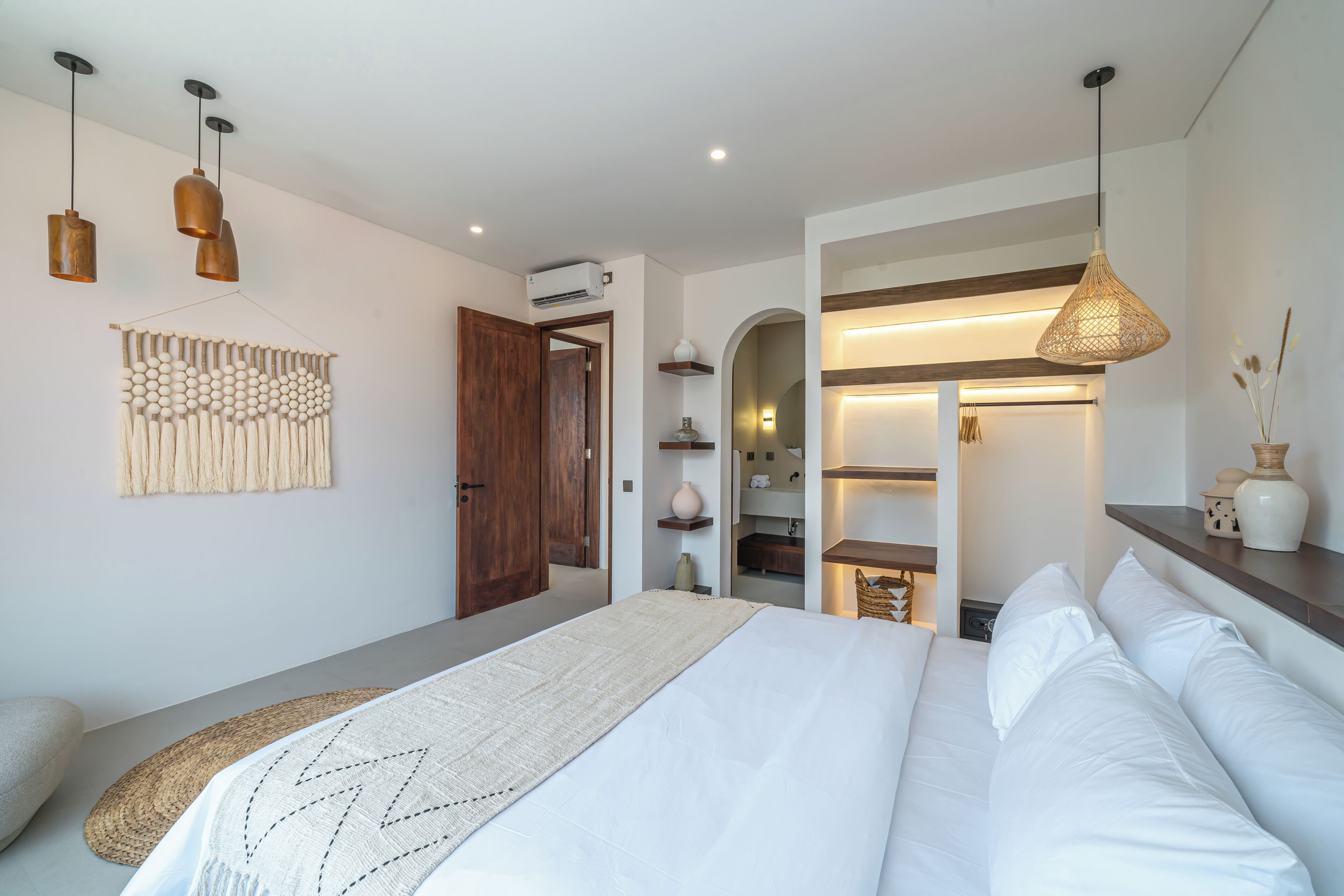 Ein modernes Schlafzimmer mit einem großen Bett, einem gewobenen Kopfteil und einer hängenden Leuchte.