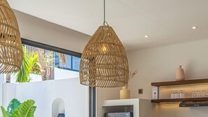 Μια σύγχρονη κουζίνα με μια κεντρική νησίδα, εντοιχισμένες συσκευές και μια τραπεζαρία με ένα σκούρο ξύλινο τραπέζι, στρωμένο για έξι άτομα.