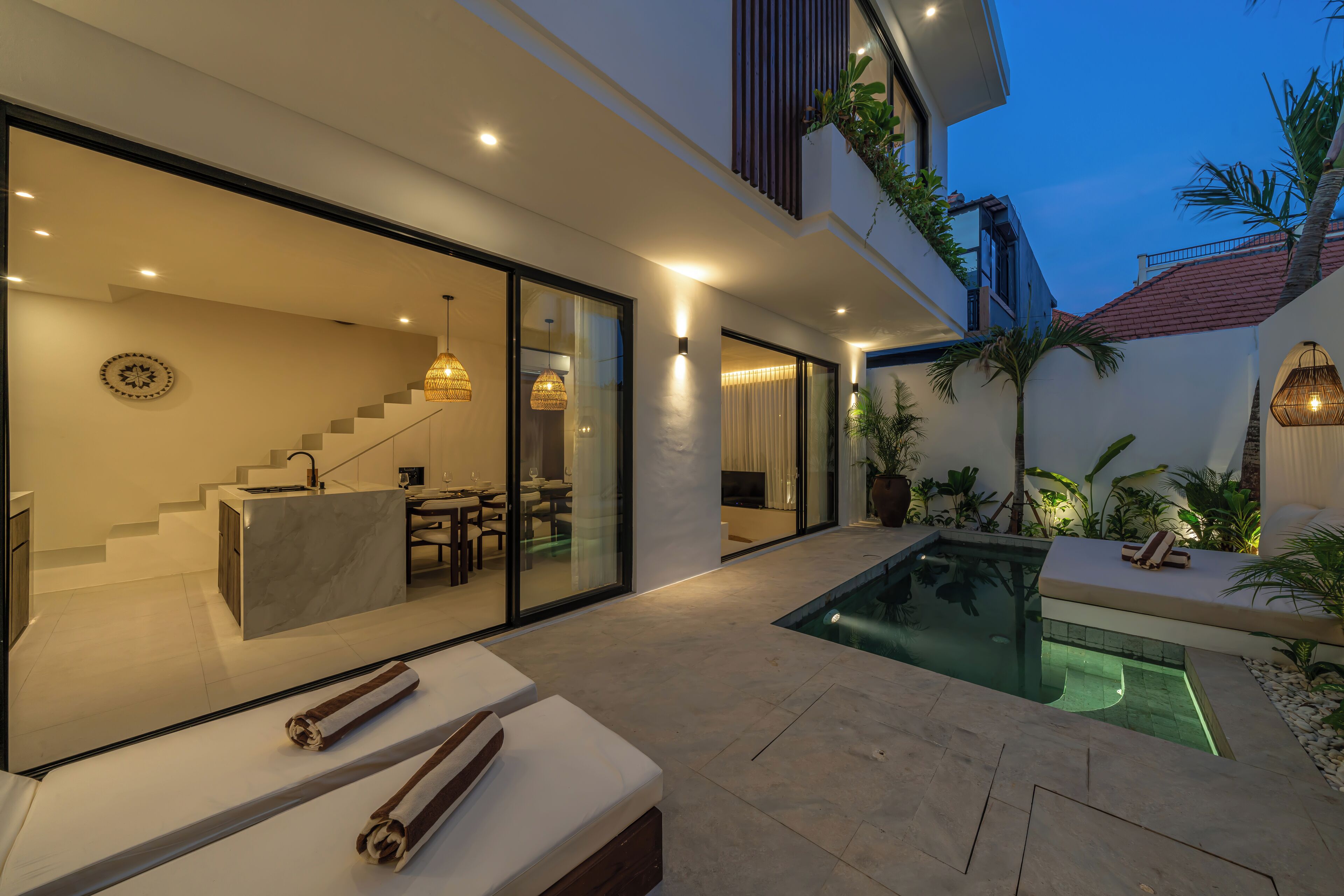 Ein modernes Haus mit Schwimmbad, Essbereich und einer Treppe, die zu einer oberen Ebene führt.
